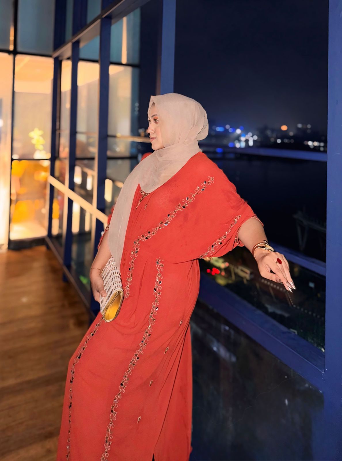 Sabrina Binte Mahbub in a coral embellished kaftan and beige hijab on a city balcony at night